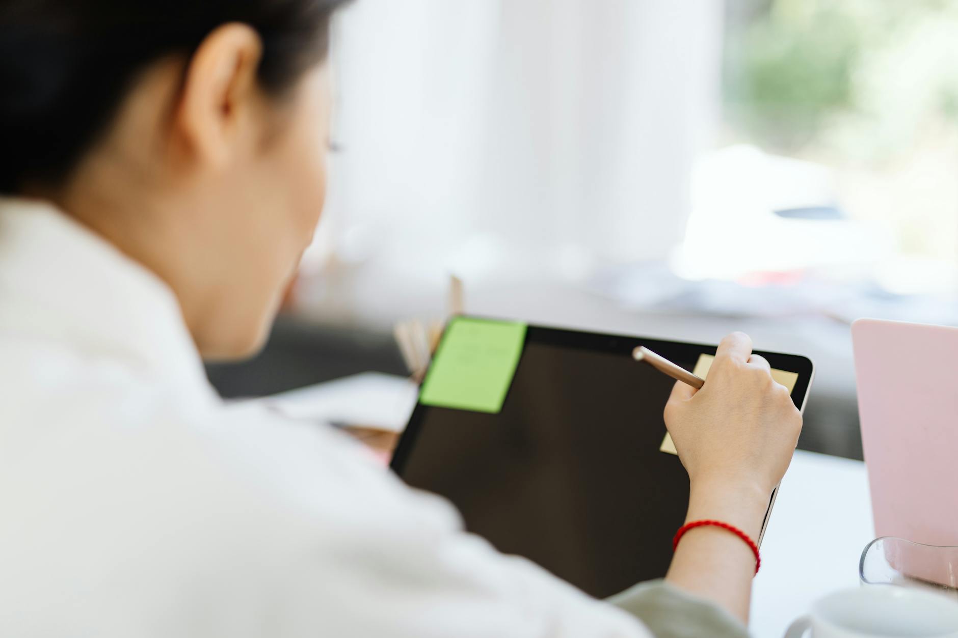 Kobieta robi cyfrowe notatki rysikiem na tablecie w nowoczesnym biurze