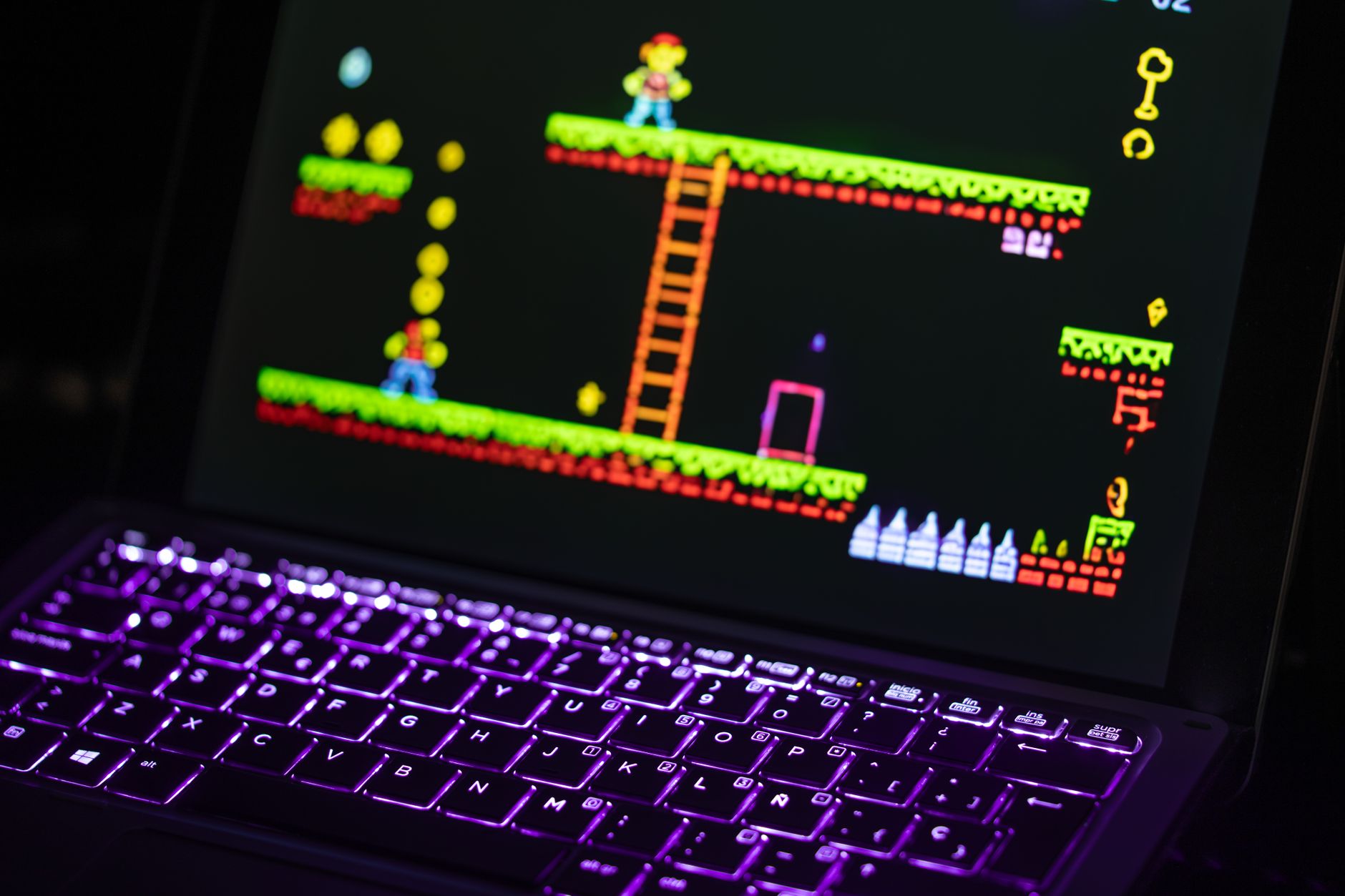 Zbliżenie laptopa z retro grą i neonowo podświetloną klawiaturą