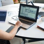 Jak czyścić dane do ML, żeby model nie uczył się błędów Osoba analizująca wykresy finansowe na laptopie w nowoczesnym biurze